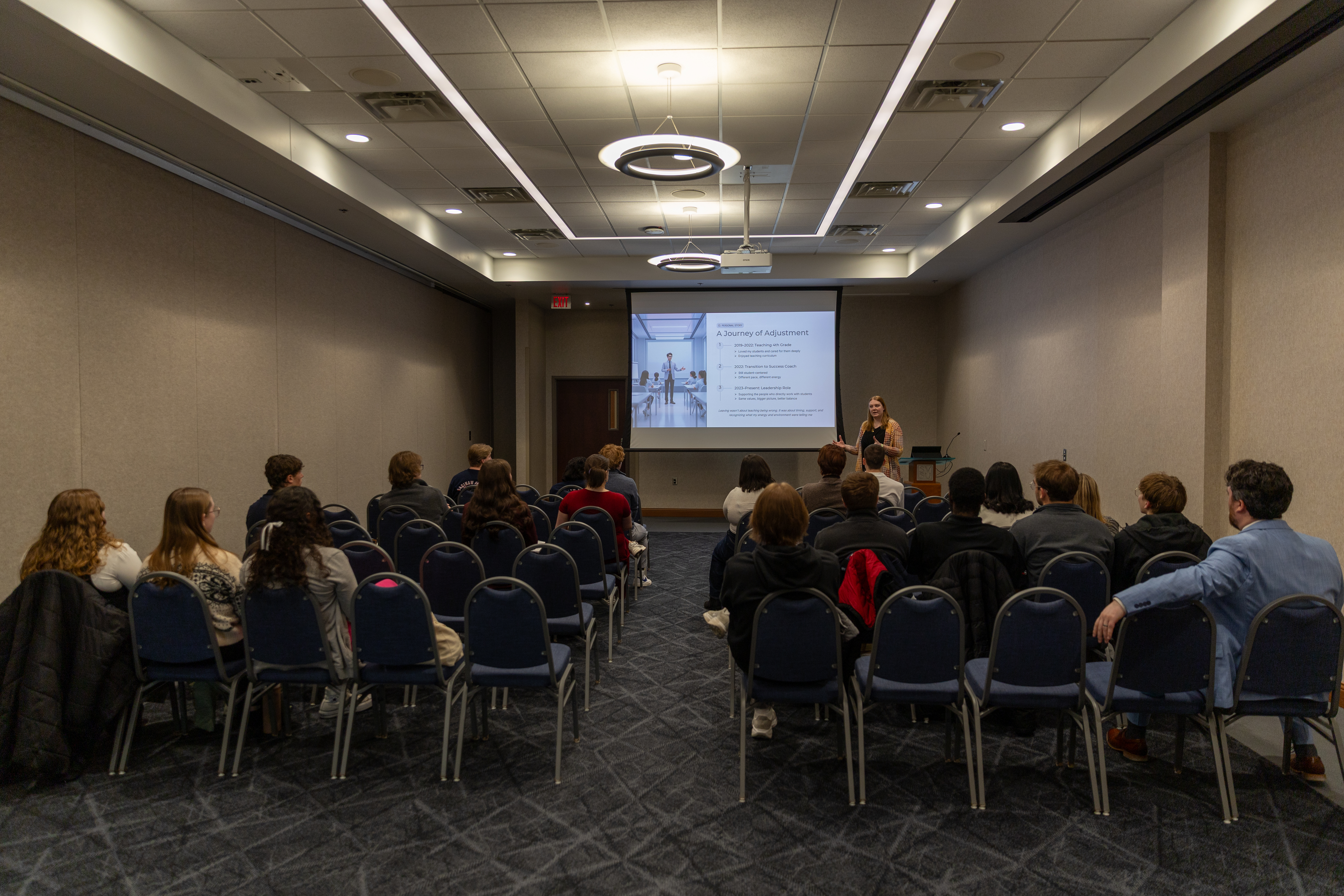 guests seated facing a presenter in front of a projector screen